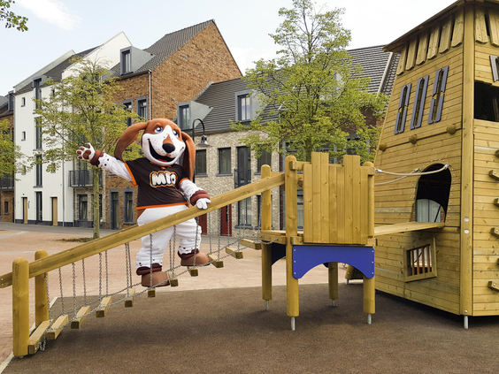Mascotte Mio de hond speelt op een houten loopbrug in de speeltuin van Dormio Resort Maastricht.