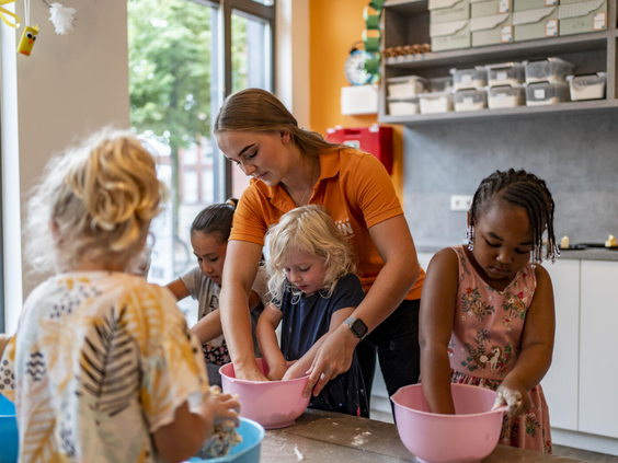 Een groep kinderen is samen met het animatieteam aan het knutselen en bakken in de Mio Kids Club van Dormio Resort Maastricht.