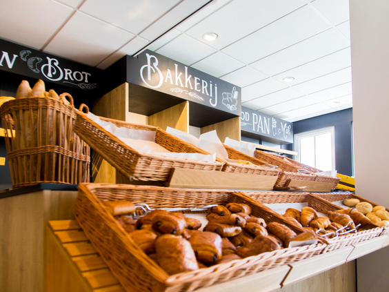 Close-up van manden gevuld met verschillende soorten verse broodjes en gebak in de bakkerij van Dormio Resort Maastricht.