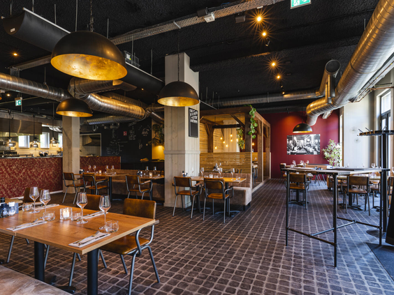 Het sfeervolle en stijlvolle interieur van restaurant 't Proeflokaal op Dormio Resort Maastricht met gedekte tafels.