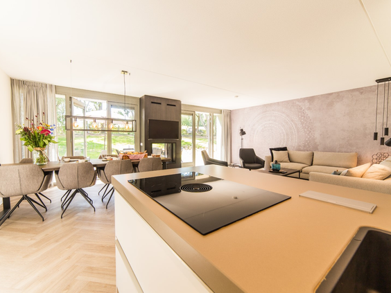 Het ruime en moderne interieur van een luxe vakantiewoning op Dormio Resort Maastricht, met een open keuken en een gezellige zithoek.