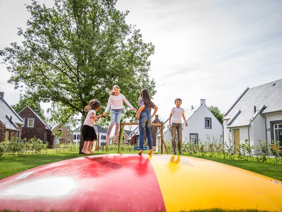 Een groep blije kinderen springt en maakt plezier op de grote, kleurrijke airtrampoline bij Dormio Resort Maastricht.