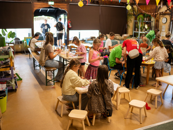 Kinderen en ouders doen mee aan een gezellige knutselactiviteit in de Kidsclub op Resort Veluwe.