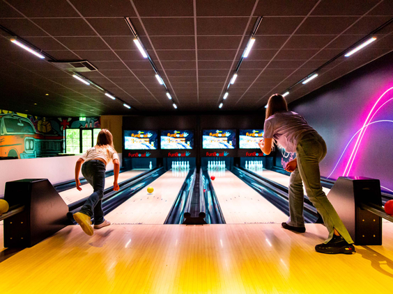 Een gezin is aan het bowlen op de fun bowlingbaan van Resort Veluwe.
