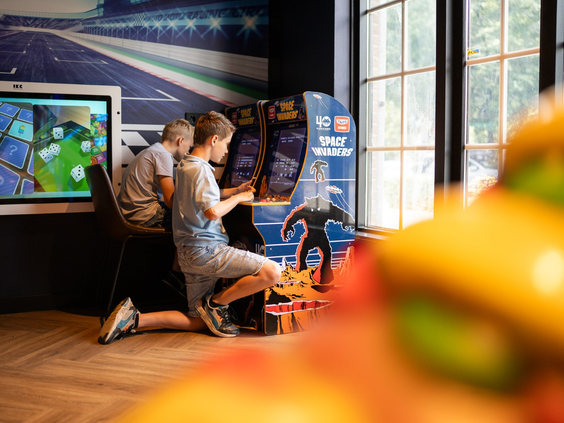 Kinderen gamen op arcadekasten in de overdekte speelhal van Resort Veluwe