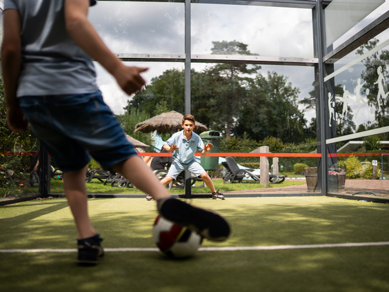 Kinderen spelen een potje voetbal op de footcourt, een pannakooi op Resort Veluwe.
