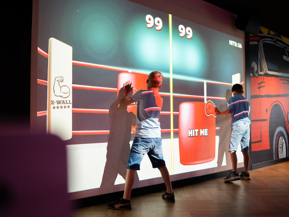 Kinderen spelen een interactief spel op de X-wall, een grote interactieve muur op Resort Veluwe.