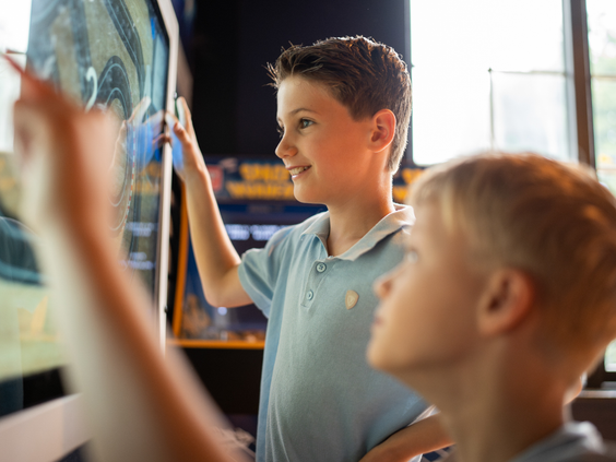 Jongens spelen spelletjes op een groot touchscreen in de gameroom