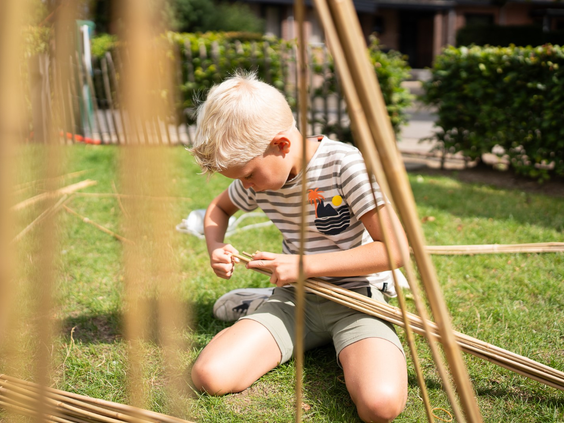 Kind bouwt met bamboestokken tijdens een activiteit van het animatieteam op Resort Veluwe.