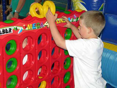 Een jongen speelt het spel reuze Vier op een Rij in de binnenspeeltuin Rudis Abenteuerland van het Rhön Park Hotel.