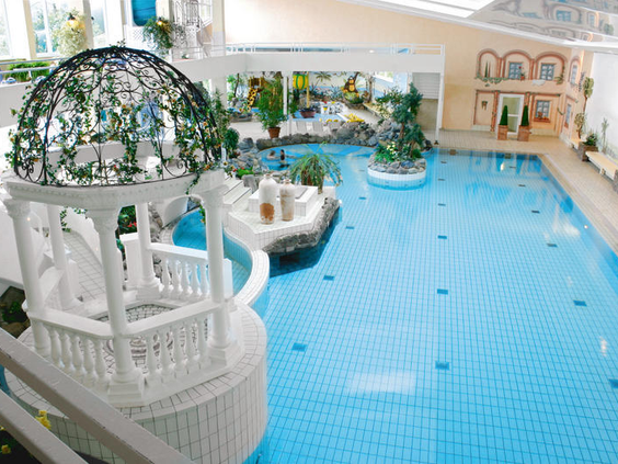 Het ruime binnenzwembad en zwemparadijs van het Rhön Park Hotel, met een speelschip en een rustige sfeer.