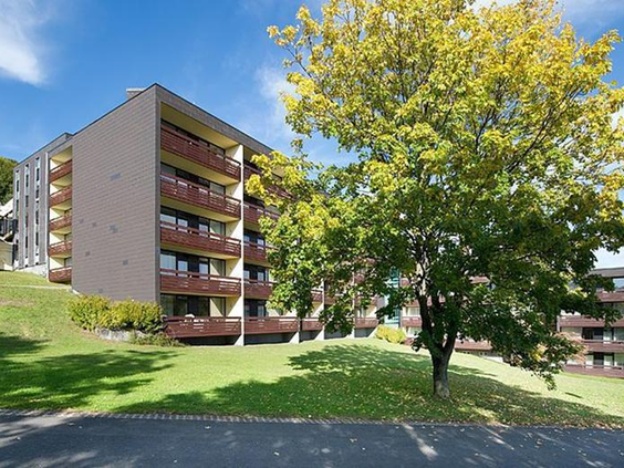 De buitenkant van een van de appartementengebouwen van Rhön Park Aktiv Resort, gelegen in het groene heuvellandschap van Beieren.
