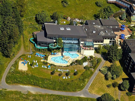 Luchtfoto van Rhön Park Aktiv Resort, met het grote buitenzwembad en de ligweide in het hart van het groene park.