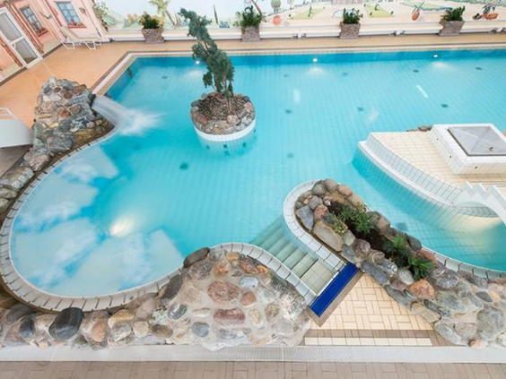 Het tropische binnenbad van zwemparadijs Rother Lagune in Rhön Park Aktiv Resort, met rotsformaties en een standbeeld van een zeepaard.