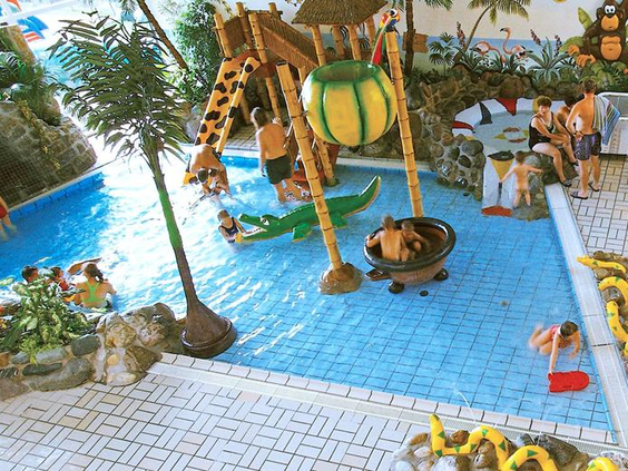 De avontuurlijke waterspeeltuin voor kinderen in zwemparadijs Rother Lagune, met palmbomen, een glijbaan en watertoestellen.
