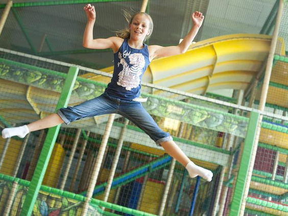 Een meisje springt blij op de trampoline in het grote klim- en klauterparadijs van Rudis Abenteuerland in Rhön Park Aktiv Resort.