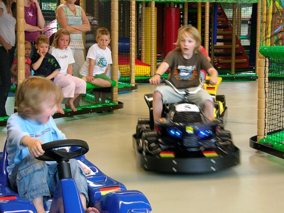 Kinderen racen tegen elkaar op elektrische skelters en karretjes in de indoorspeeltuin Rudis Abenteuerland.