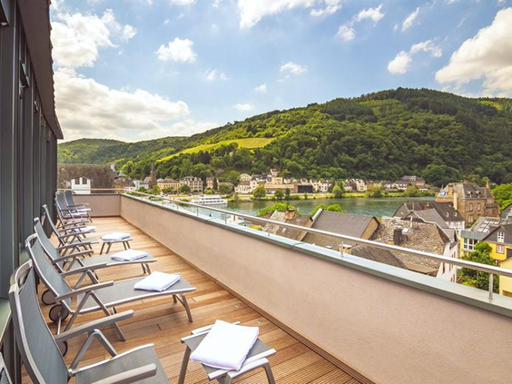 Het zonovergoten dakterras van Hotel Bellevue met ligbedden en een panoramisch uitzicht over de Moezelvallei.