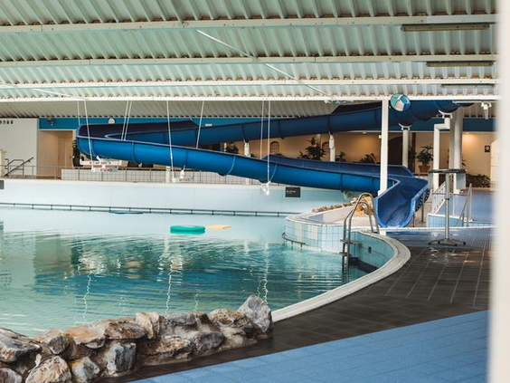 Het subtropische binnenzwembad van Roompot Beach Resort met een grote blauwe waterglijbaan en golfslagbad.