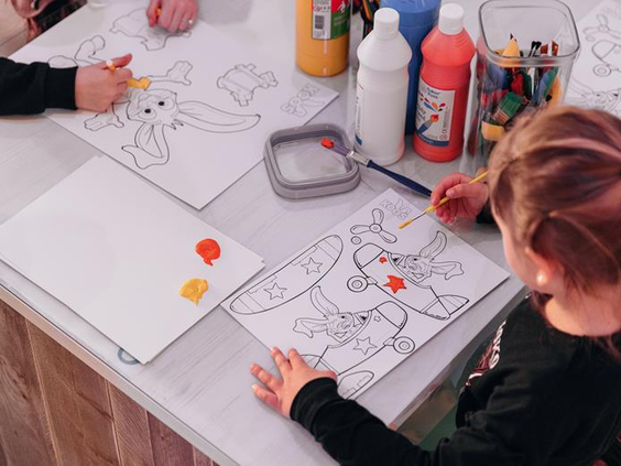 Kinderen zijn creatief bezig en verven een kleurplaat van Koos Konijn met vingerverf in de knutselclub van Roompot.