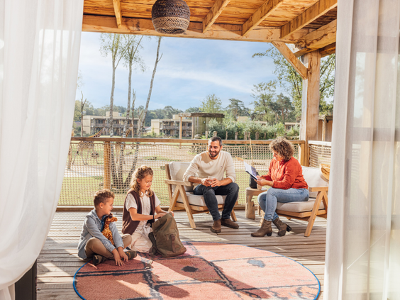 Een gezin geniet van het uitzicht op de savanne vanaf de veranda van hun lodge in Safari Hotel Beekse Bergen