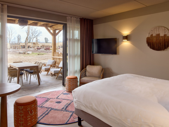 Hotelkamer in Safari Hotel Beekse Bergen met uitzicht op de savanne met wilde dieren vanaf het terras.