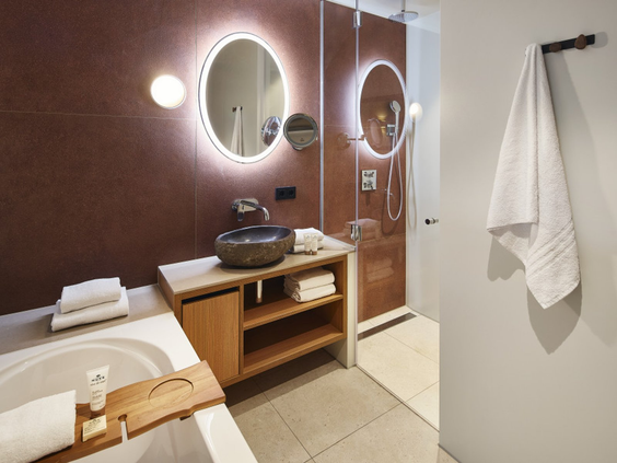 Moderne badkamer in het Safari Hotel met een ruime inloopdouche, wastafel en verlichte spiegel.