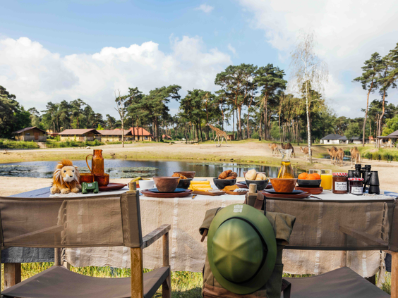 Gedekte ontbijttafel voor een unieke overnachting tussen de wilde dieren met uitzicht op de savanne van Safari Resort Beekse Bergen