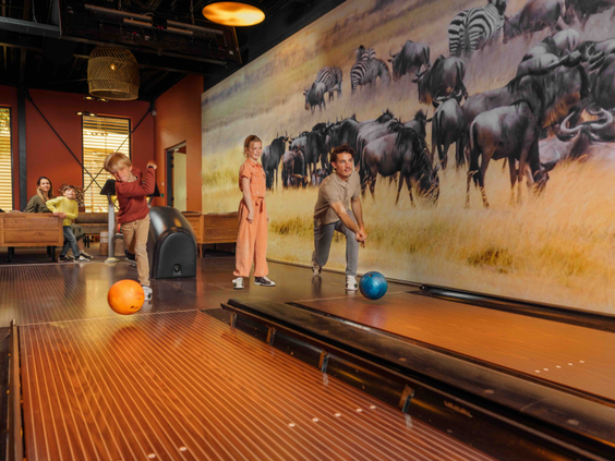 Gezin met kinderen bowlen op twee bowlingbanen en hebben plezier met safari thema