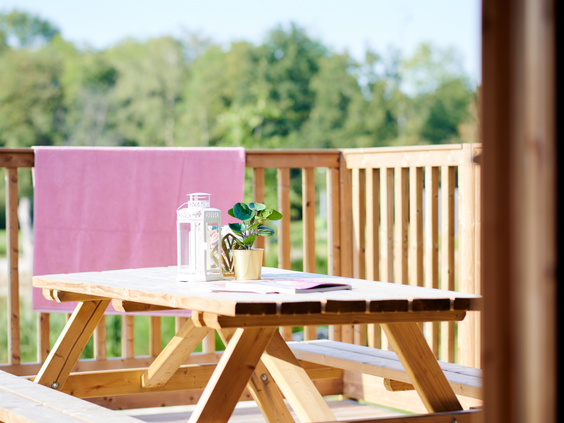 Een gezellig gedekte picknicktafel op de veranda van een safaritent, klaar voor een heerlijke maaltijd in de buitenlucht.