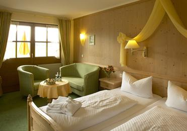 Een sfeervolle slaapkamer in traditionele Beierse stijl in Sonnhofs Ferienresidenz, met een comfortabel bed en een hemeltje.