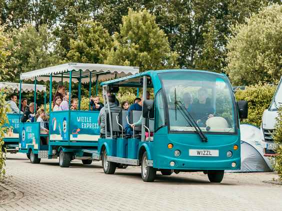 De blauwe Strand Express, het treintje van Strandpark De Zeeuwse Kust, rijdt met gasten over het vakantiepark richting het strand.