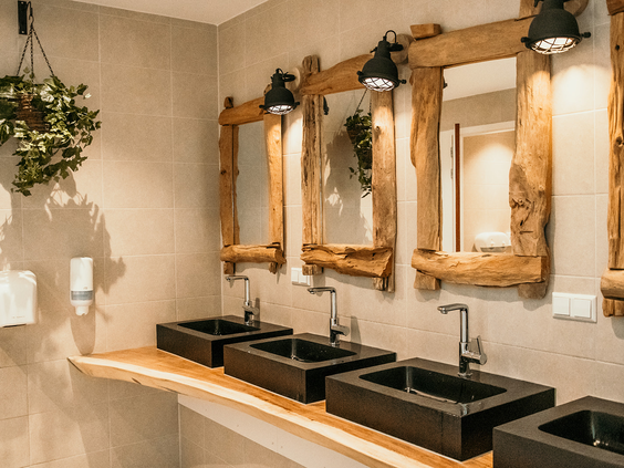 Het luxe en moderne sanitairgebouw van Strandpark De Zeeuwse Kust, met stoere houten spiegels en zwarte wasbakken.