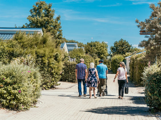 Familie wandelt over een pad op het groen aangelegde Strandpark De Zeeuwse Kust, genietend van een ontspannen vakantie in de buitenlucht.