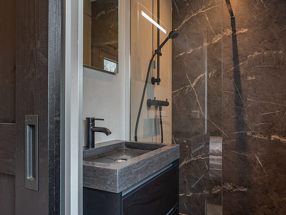 Moderne en luxe badkamer met een marmerlook inloopdouche en stenen wastafel in een chalet op Strandpark De Zeeuwse Kust.