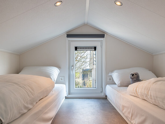 Knusse kinderslaapkamer met twee aparte bedden in een vakantiehuisje op Strandpark De Zeeuwse Kust, ideaal voor een gezinsvakantie.