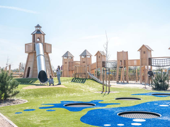 Grote buitenspeeltuin met een hoge vuurtoren met glijbaan en een houten klimkasteel bij Strandpark De Zeeuwse Kust.