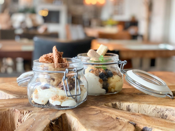 Twee heerlijke dessertjes, 'toetjes in een potje', geserveerd op een houten plank in het restaurant van Strandpark De Zeeuwse Kust.
