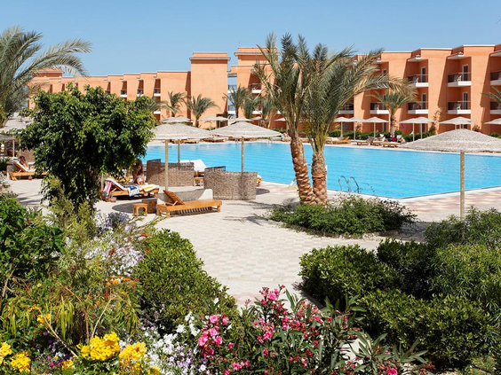 Het zwembad van Three Corners Sunny Beach Resort in Egypte, omgeven door een prachtig aangelegde tuin met palmbomen en bloemen.