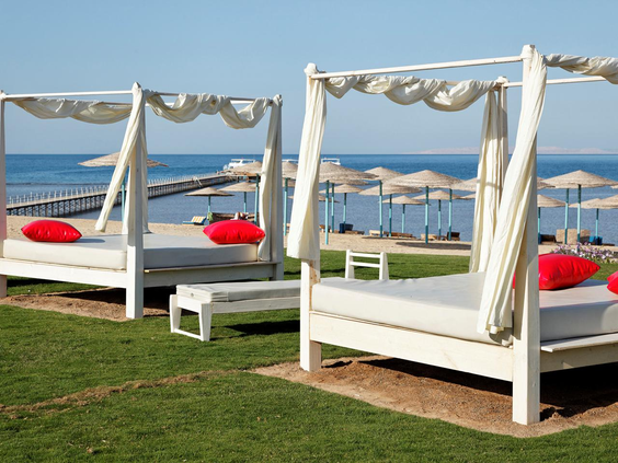 Luxe witte cabanas met rode kussens en uitzicht op de Rode Zee bij Three Corners Sunny Beach Resort in Hurghada.
