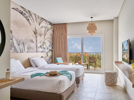 Een moderne, lichte tweepersoonskamer met twee losse bedden en balkon bij Three Corners Sunny Beach Resort.