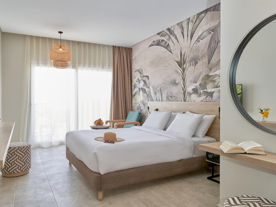 Een stijlvol ingerichte hotelkamer met een tweepersoonsbed en tropisch behang bij Three Corners Sunny Beach Resort.