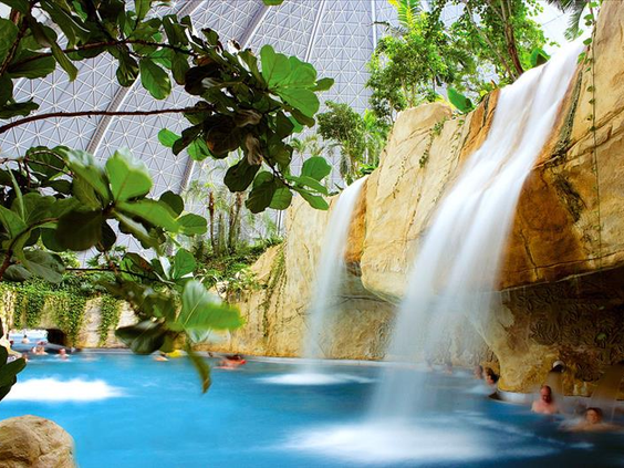 Een grote waterval stort in het helderblauwe water van de Bali Lagune, omringd door rotsen en tropische planten in de koepel van Tropical Islands.