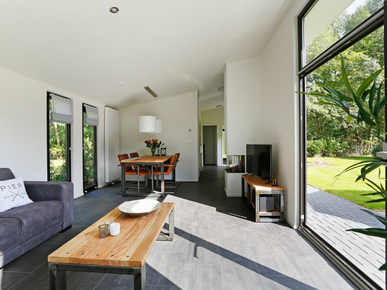 Het ruime interieur van een Regge Cottage met de grote glazen deuren open naar de tuin, wat zorgt voor een open en lichte sfeer.