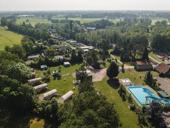 Een brede luchtfoto van Vakantiecentrum 't Schuttenbelt, met een overzicht van de camping, het buitenzwembad en de ligging in het groene Twentse landschap.