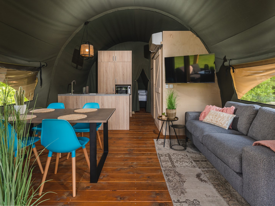 Het sfeervolle interieur van een luxe lodge met een complete keuken, eethoek en een gezellige zithoek met bank.