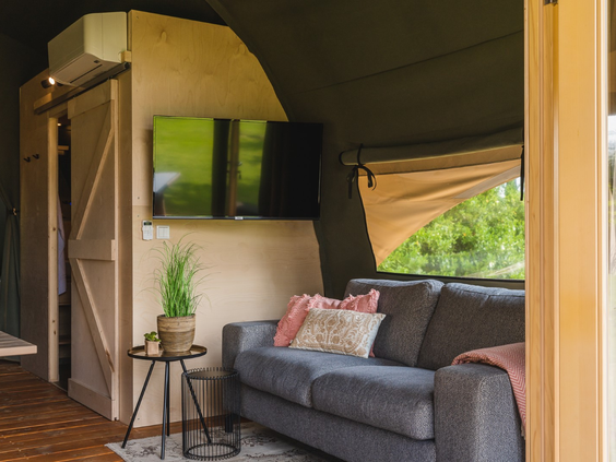 Een close-up van de gezellige zithoek in een lodge, met een comfortabele bank en een tv voor een ontspannen avond.