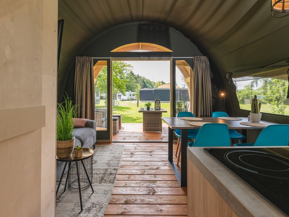 Een kijkje vanuit de ruime en sfeervolle lodge op 't Schuttenbelt, met open deuren naar het terras en een gezellige eethoek.