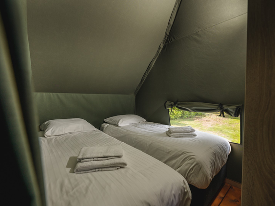 De knusse slaapkamer met twee opgemaakte bedden in een luxe lodge, waar kinderen heerlijk kunnen slapen na een dag spelen.