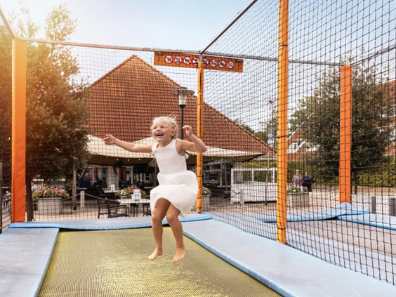Een meisje springt vrolijk op een van de trampolines in de speeltuin van Vakantiepark Aquadelta.